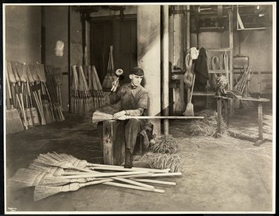 Blind man placing iron hoops on brooms at the Bourne Memorial Building, New York, 1921 by Byron Company